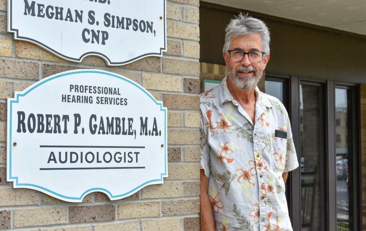 Bob Gamble stands next to his office sign on June 14, two days before he saw his last patient. Now that he has retired, he plans to “catch up on my to-do list and put a dent in my wife’s.”