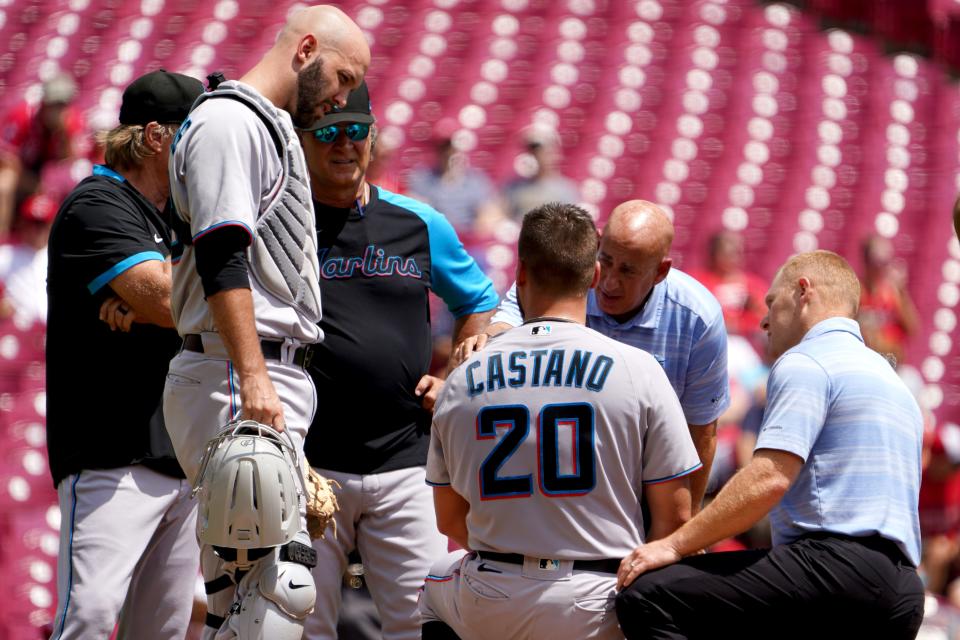 The Miami Marlins medical staff checks on Miami Marlins starting pitcher Daniel Castano (20), who fell to his knees after a ball off the bat of Cincinnati Reds third baseman Donovan Solano (7) (not pictured) during the first inning of a baseball game, Thursday, July 28, 2022, at Great American Ball Park in Cincinnati. 