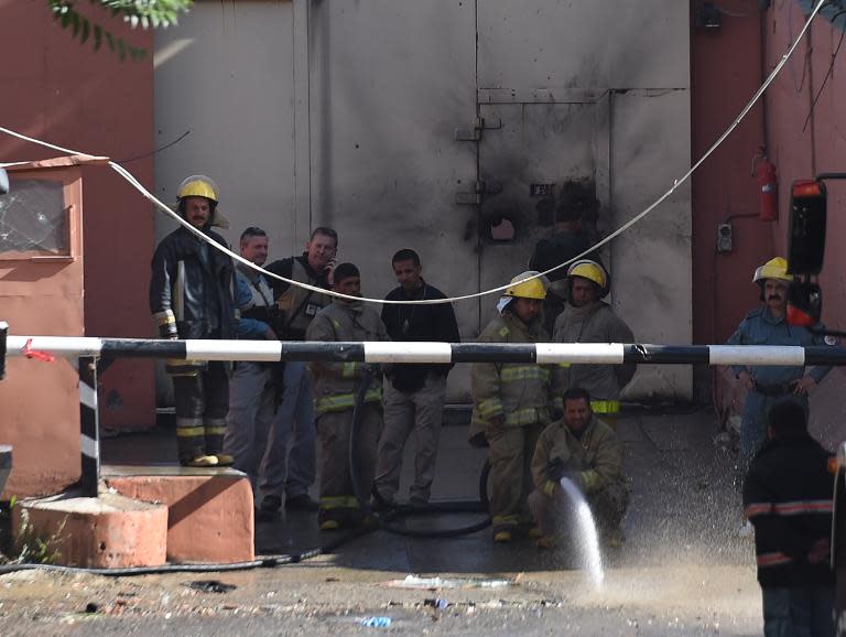 Afghan firefighters spray water in front of the gates of the Heetal Hotel in Kabul on May 27, 2015 after an all-night Taliban siege of the guesthouse owned by a prominent political family