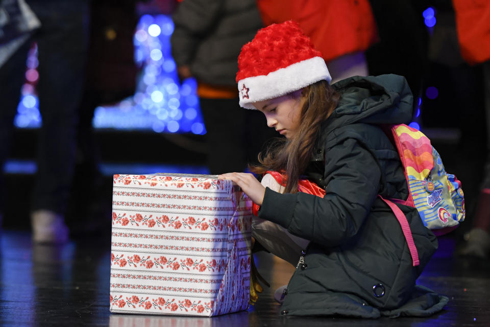 A girl looks at a present received after a Christmas show for children in care, in Bucharest, Romania, Wednesday, Dec. 18, 2019. Romania has more than 50 thousand children in state care, according to recent statistics quoted by local media. (AP Photo/Andreea Alexandru)
