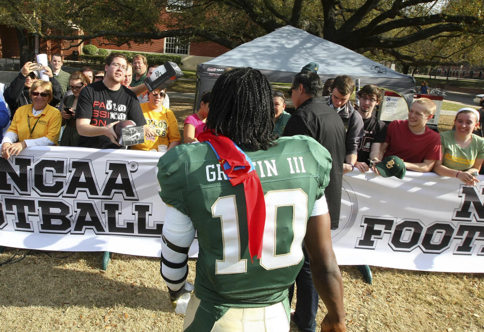 Heisman Trophy winner and former quarterback Robert Griffin III walks over to fans with a pair of Superman socks given to him by a fan on the Baylor University campus, Monday, Feb. 27, 2012 where he was at a photo session for the EA Sports NCAA Football 13 video game to be released in July. Video-game developer EA Sports is breaking back into the college football world 11 years after lawsuits over using players’ likeness without compensation froze the franchise. (Jerry Larson/Waco Tribune-Herald via AP)