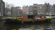 People wait on bridges for a free bouquet of tulips in Amsterdam, Netherlands, Saturday, Jan. 15, 2022. Stores across the Netherlands cautiously re-opened after weeks of coronavirus lockdown, and the Dutch capital's mood was further lightened by dashes of color in the form of thousands of free bunches of tulips handed out by growers sailing with a boat through the canals. (AP Photo/Peter Dejong)