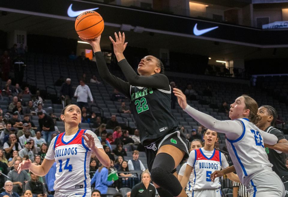 St. Mary's Jordan Lee, center, goes to the hoop between Folsom's Kamryn Mafua, left, and Dixie Mclanahan during the Sac-Joaquin Section girls basketball championship game at Golden One Center in Sacramento on Feb. 21. 2024. St. Mary's won 57-51.