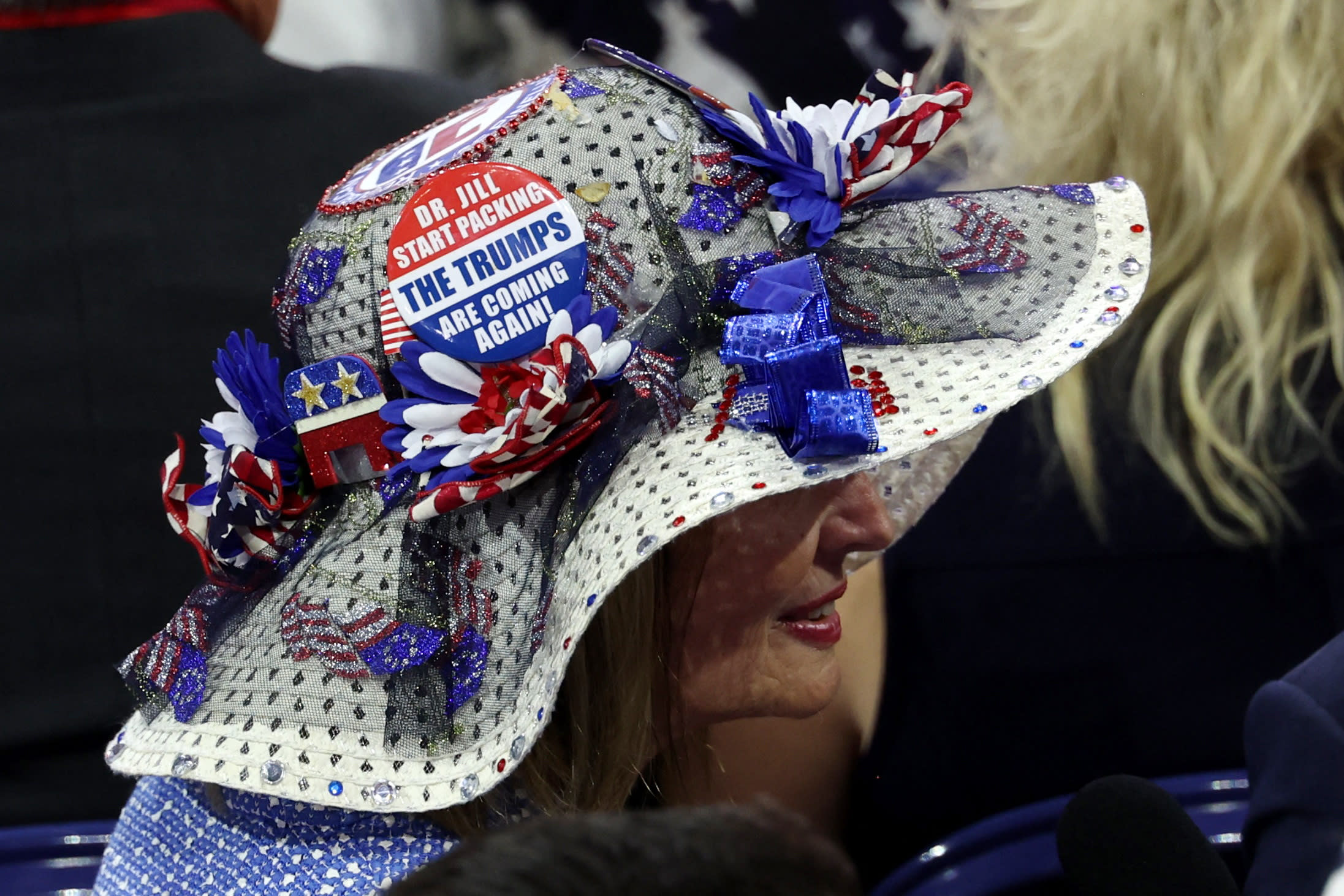 A woman wears a hat with a button that reads 