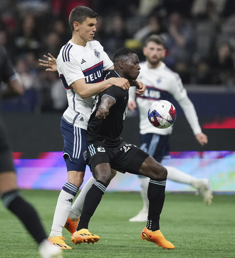 Vancouver Whitecaps' Ranko Veselinovic, left, and Minnesota United's Mender Garcia vie for the ball during the second half of an MLS soccer match in Vancouver, British Columbia, Saturday, May 6, 2023. (Darryl Dyck/The Canadian Press via AP)