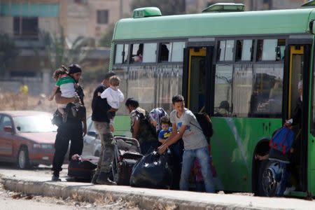 Syrian rebels and their families carry their luggage into a bus to evacuate the besieged Waer district in the central Syrian city of Homs, after a local agreement reached between rebels and Syria's army, Syria September 22, 2016. REUTERS/Omar Sanadiki