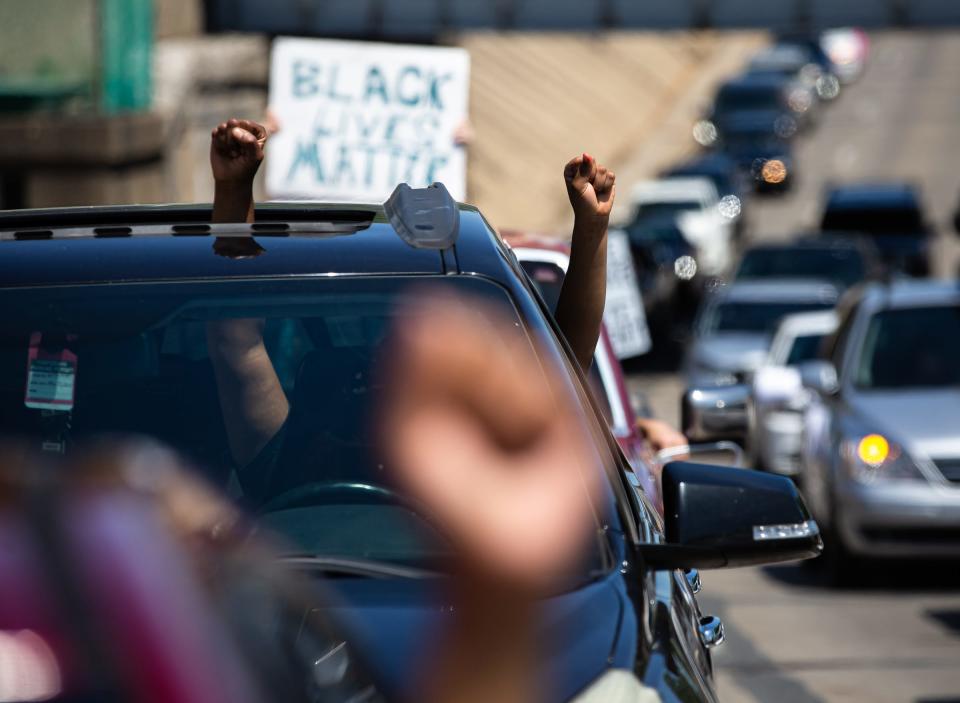 People hold up their fists through their car windows as a parade of cars comes down South Grand Avenue during the Solidarity Vehicle Procession hosted by Black Lives Matters Springfield, Sunday, May 31, 2020, in Springfield, Ill.