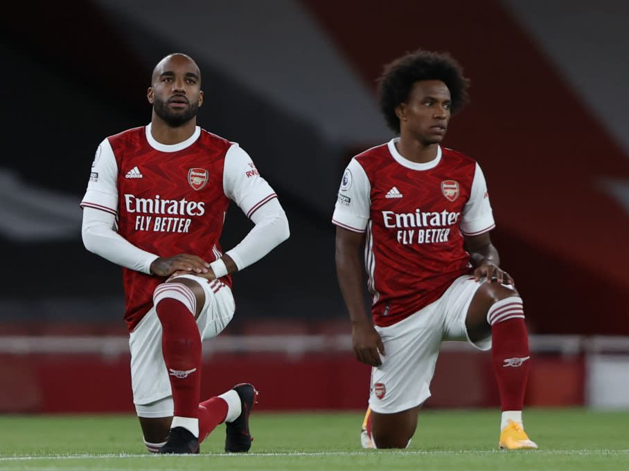 Alexandre Lacazette and Willian of Arsenal take a knee prior to their Premier League fixture against West HamPOOL/AFP via Getty Images