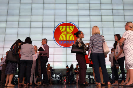 Delegates stand next to the ASEAN Summit signage at Suntec Convention Centre in Singapore, November 12, 2018. REUTERS/Athit Perawongmetha