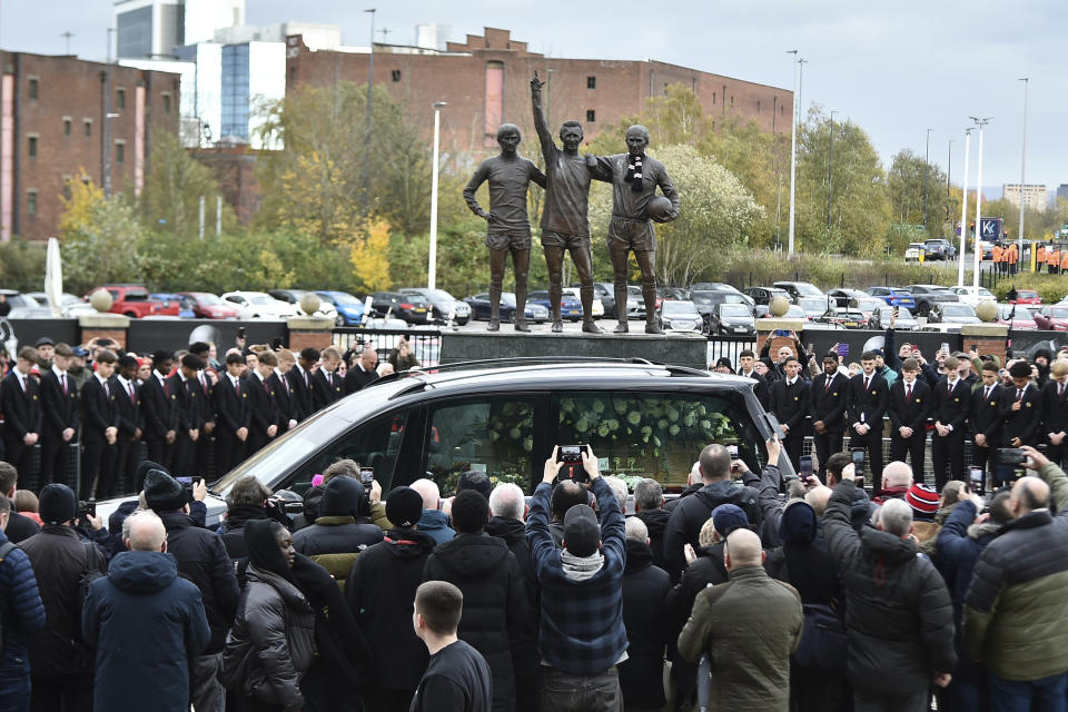 El cotejo fúnebre de Bobby Charlton pasa frente a la estatua del tío de Charlton, George Best y Denis Law afuera del Old Trafford antes del funeral en la Catedral de Manchester el lunes 13 de noviembre del 2023. (AP Foto/Rui Vieira)