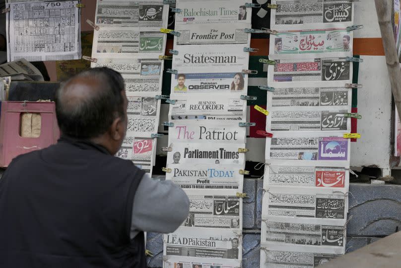 A Pakistani checks morning newspapers covering front page story of Iran's strike, at a stall in Islamabad, Pakistan on Thursday