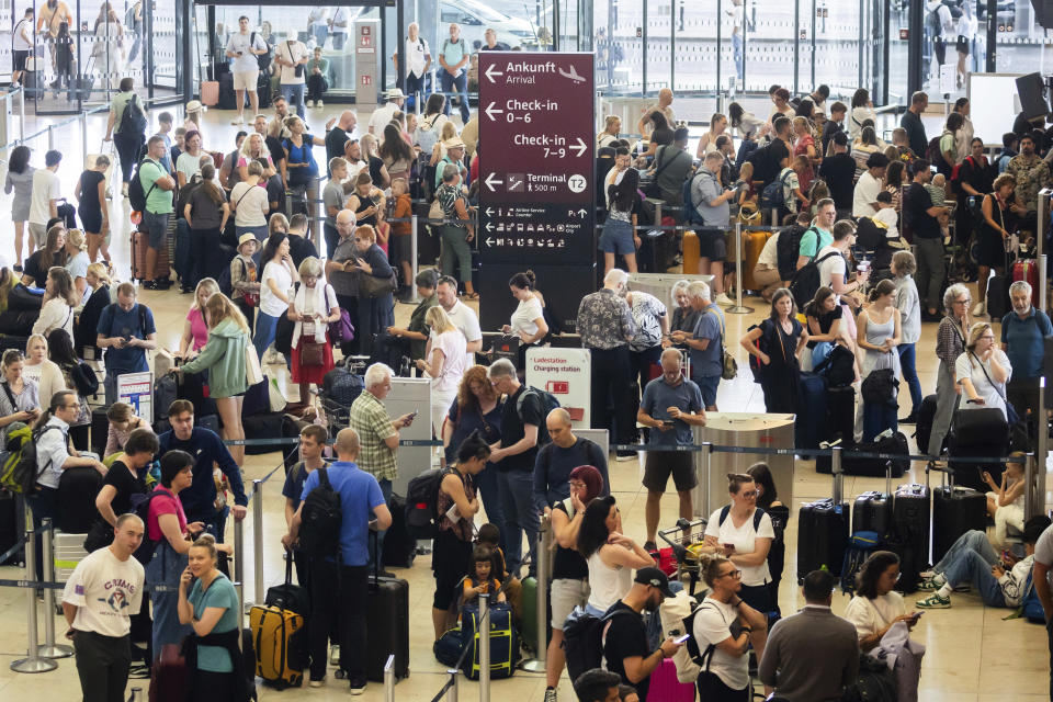 Passengers wait in front of check-in counters at the capital's Berlin Brandenburg Airport, in Schönefeld, Germany, Friday, July 19, 2024, after a widespread technology outage disrupted flights, banks, media outlets and companies around the world. (Christoph Soeder/dpa via AP)