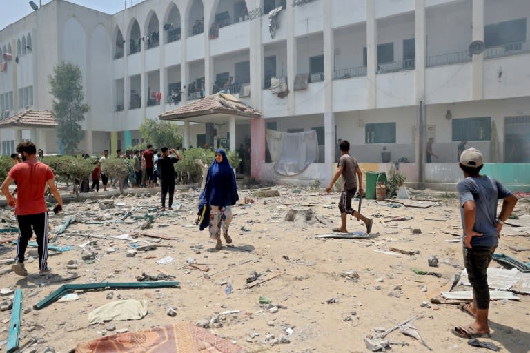 Palestinos caminan entre escombros tras un bombardeo israelí contra la escuela Khadija en Deir al-Balah, en el centro de Gaza, el 27 de julio de 2024 (AFP)