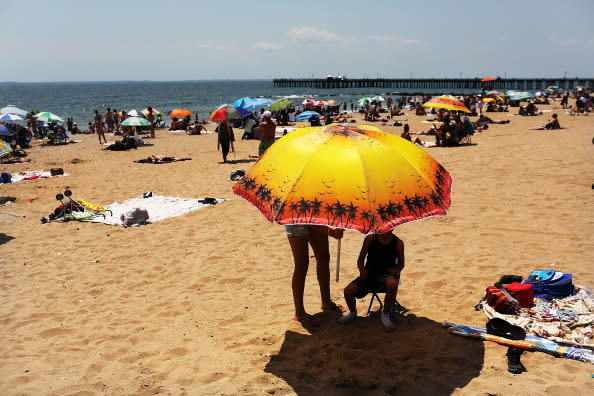 People enjoy the beach at Coney Island on July 12, 2012 in the Brooklyn borough of New York City. Coney Island has until recently been viewed as a seedy and dilapidating seaside park, however, it is going through a gradual transition which many compare to the renovation of Times Square. In order to accommodate more shops and residential buildings, the Michael Bloomberg administration rezoned Coney Island in 2009. The city also bought seven acres of prime Coney Island real estate promising approximately $150 million in infrastructure upgrades in the area. A recent study found that Coney Island's Luna Park had 640,000 visitors in 2011, the most since Steeplechase Park closed in 1964. (Photo by Spencer Platt/Getty Images)