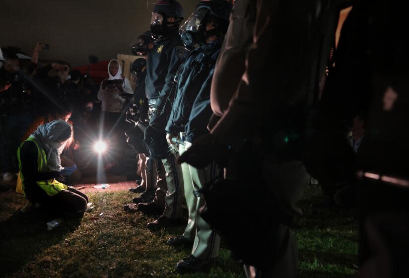 LOS ANGELES, CALIFORNIA - May 1: A woman prays in front of CHP officers next tot he pro-Palestinian encampment at UCLA early Wednesday morning. (Wally Skalij/Los Angeles Times)