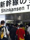 Passengers wait for information outside the shinkansen bullet train ticket barrier at Tokyo station on June 30, 2015 after service was disrupted due to an apparent suicide attempt on board