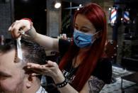 Barber Kinga Rutkowska, 22, cuts hair at a barbershop in Warsaw