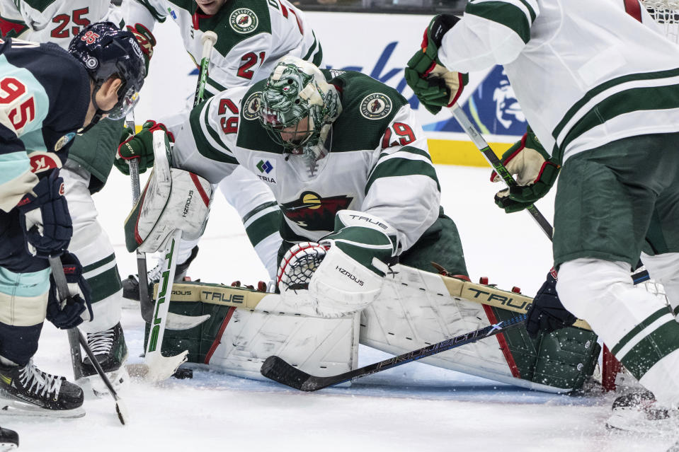Minnesota Wild goalie Marc-Andre Fleury makes a save on a shot by Seattle Kraken forward Andre Burakovsky, left, during the second period of an NHL hockey game Saturday, Feb. 24, 2024, in Seattle. (AP Photo/Stephen Brashear)