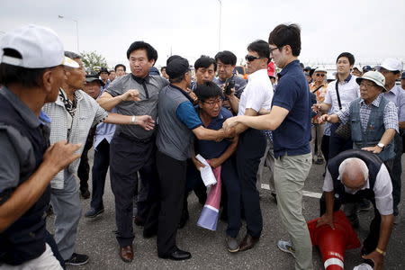 Police take a North Korean flag away from a man during an anti-North Korea rally at a checkpoint on the Grand Unification Bridge which leads to the truce village Panmunjom, just south of the demilitarized zone separating the two Koreas, in Paju, South Korea, August 24, 2015. REUTERS/Kim Hong-Ji