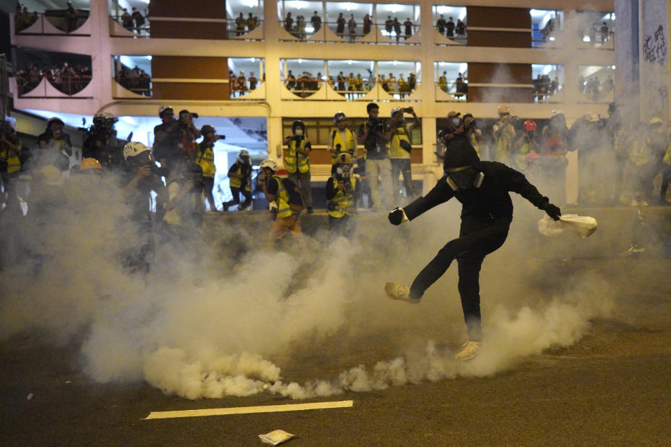 A protestor kicks a tear gas canister during confrontation in Hong Kong Sunday, July 21, 2019. Hong Kong police launched tear gas at protesters Sunday after a massive pro-democracy march continued late into the evening. The action was the latest confrontation between police and demonstrators who have taken to the streets to protest an extradition bill and call for electoral reforms in the Chinese territory. (Ming Ko/HK01 via AP)