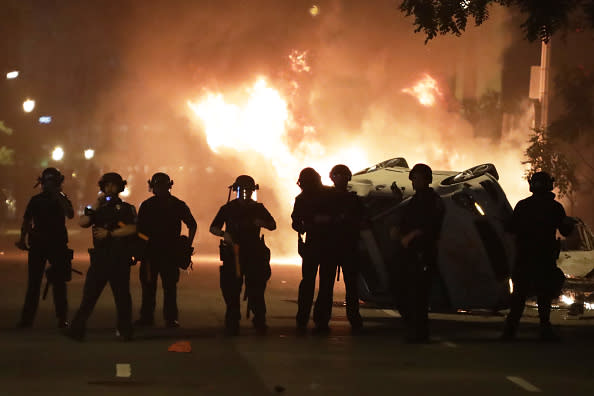 Police holds a perimeter in front of burning and rolled over vehicles during a protest near the White House in Washington, DC. 