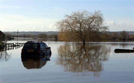 A semi submerged car is seen in urban landscape taken in the flooded Somerset village of Moorland February 16, 2014. British ministers will meet representatives of the insurance industry on Tuesday, February 18, who will brief them on their progress in dealing with victims of winter floods across southern England. REUTERS/Cathal McNaughton