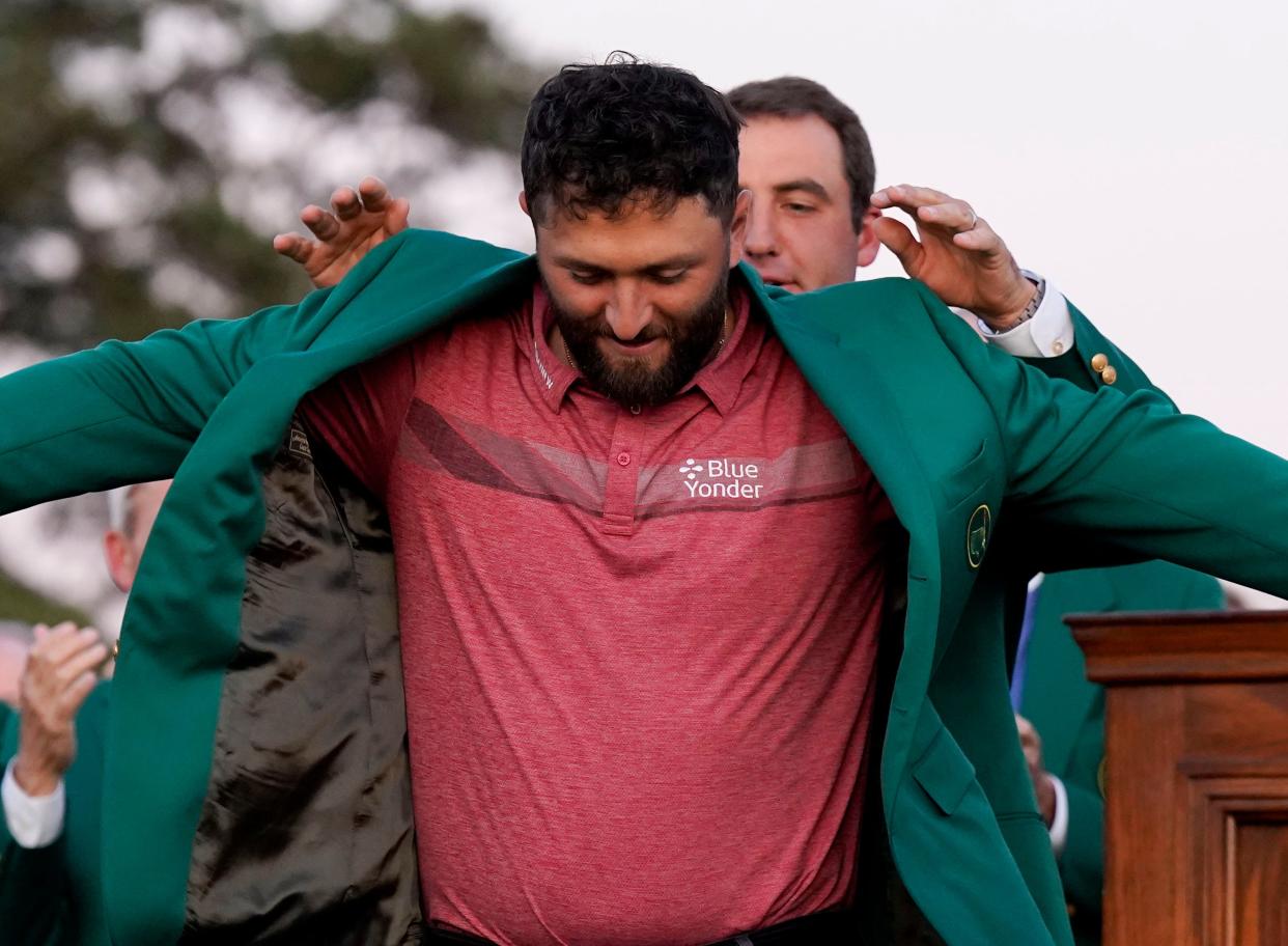 2022 Masters champion Scottie Scheffler helps Jon Rahm into his green jacket during the green jacket ceremony at The Masters golf tournament on Sunday.