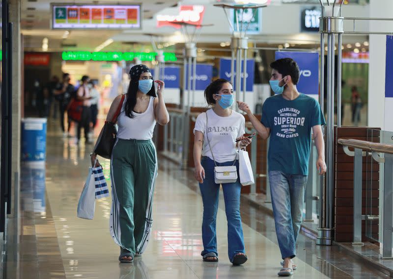 People wearing masks walk with shopping bags inside a mall as India eases lockdown restrictions that were imposed to slow the spread of the coronavirus disease (COVID-19), in New Delhi