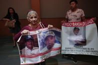 In this Feb. 12, 2020 photo, Ma Elena Rodriguez Gonzalez holds posters that show her two missing sons, following a meeting between the city mayor and the "A tu Encuentro" collective who are searching for their missing loved ones, in Irapuato, Guanajuato state, Mexico. While in other parts of Mexico, protesters, pressure groups or cartel gunmen regularly block roads and railway lines, that just doesn't happen in Guanajuato. While the state isn't very strenuous in investigating homicides, protesters can be hit with the toughest possible charges, including terrorism. (AP Photo/Rebecca Blackwell)