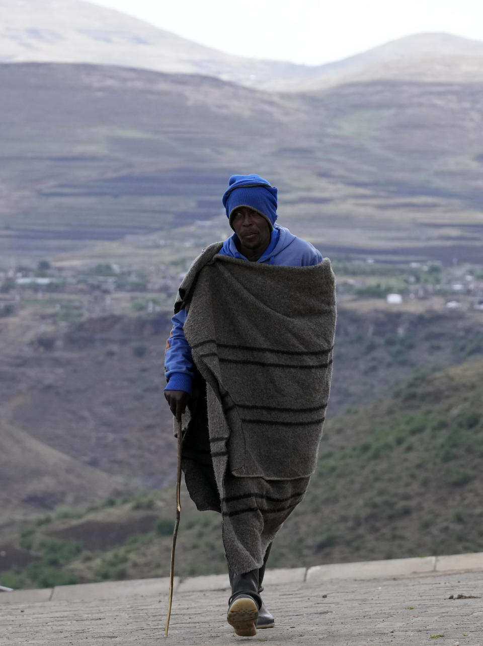 A man covered with a blanket leaves the voting station after casting his vote at a polling station in Thaba-Tseka District, 82km east of Maseru, Lesotho, Friday, Oct. 7, 2022. Voters across Lesotho are heading to the polls Friday to elect a leader to find solutions to high unemployment and crime. (AP Photo/Themba Hadebe)
