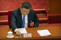 Chinese President Xi Jinping reaches to vote on a piece of national security legislation concerning Hong Kong during the closing session of China's National People's Congress (NPC) in Beijing, Thursday, May 28, 2020. China's ceremonial legislature has endorsed a national security law for Hong Kong that has strained relations with the United States and Britain. (AP Photo/Mark Schiefelbein)