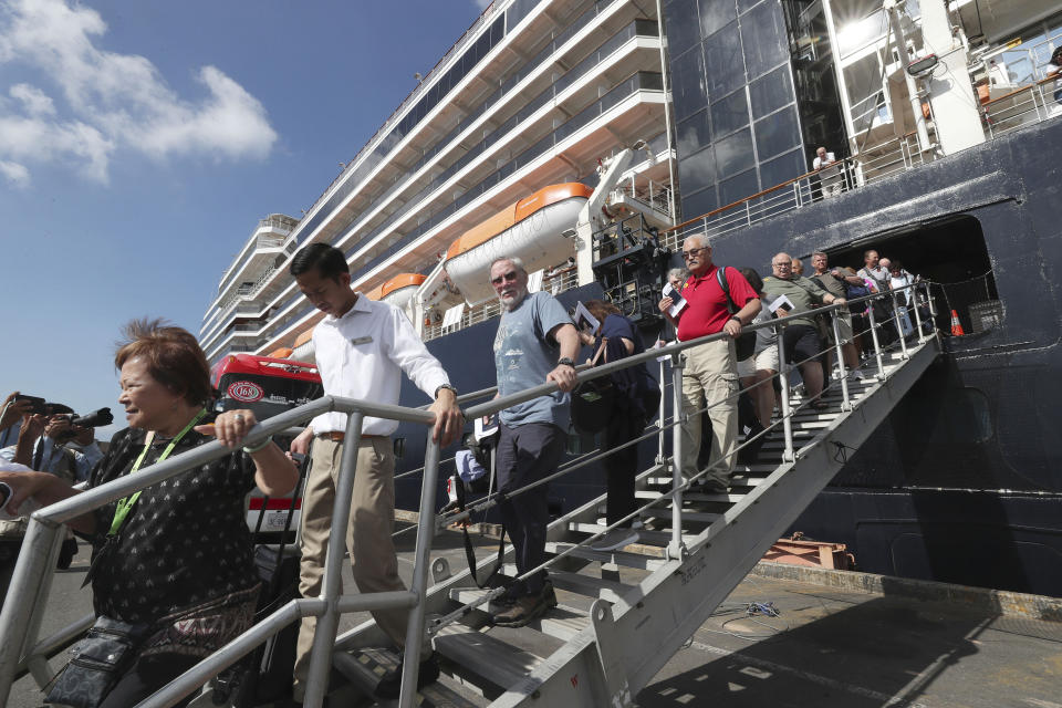 Passengers of the MS Westerdam disembark at the port of Sihanoukville, Cambodia, Saturday, Feb. 15, 2020. After being stranded at sea for two weeks because five ports refused to allow their cruise ship to dock, the passengers of the MS Westerdam were anything but sure their ordeal was finally over. (AP Photo/Heng Sinith)