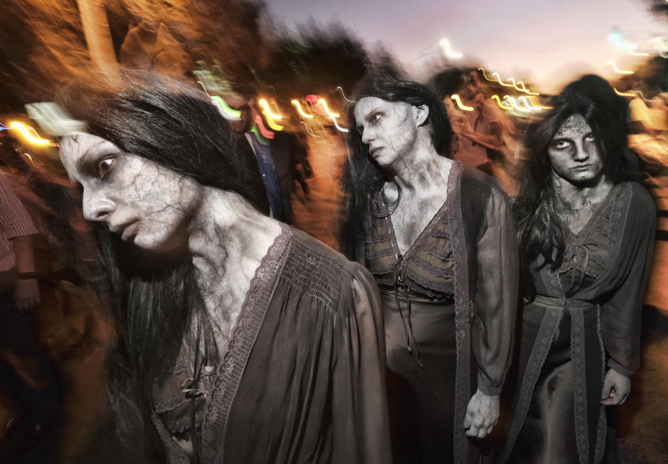 FILE - In this Oct. 31, 2018, file photo, zombie sisters maneuver their way down Santa Monica Boulevard in West Hollywood, Calif., during the West Hollywood Carnaval and Halloween Parade. The holiday so many look forward to each year is going to look different in the pandemic as parents and the people who provide Halloween fun navigate a myriad of restrictions and safety concerns. (AP Photo/Richard Vogel, File)