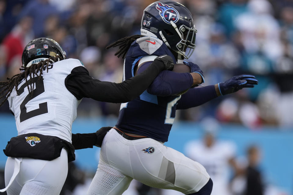 Tennessee Titans running back Derrick Henry, right, is tackled by Jacksonville Jaguars safety Rayshawn Jenkins, left, after a long gain during the second half of an NFL football game Sunday, Jan. 7, 2024, in Nashville, Tenn. (AP Photo/George Walker IV)