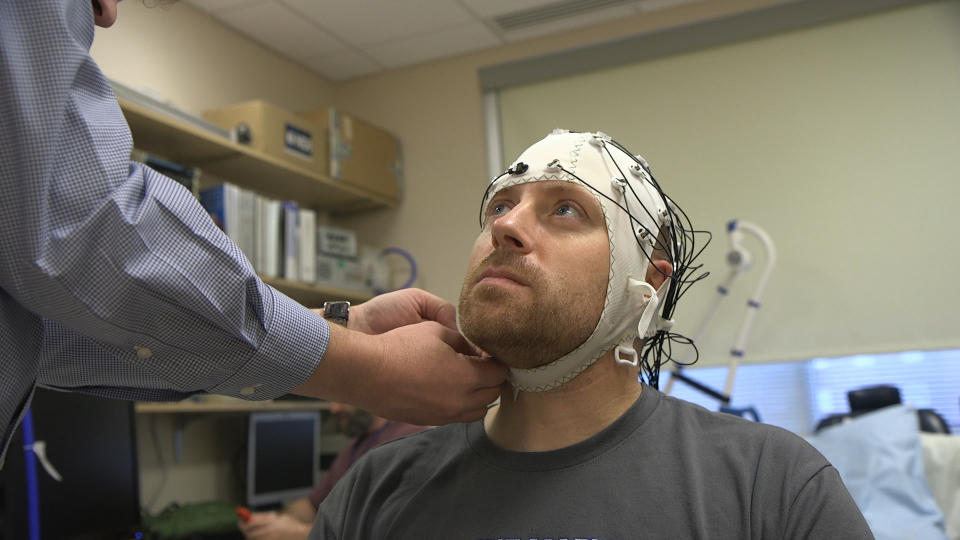 In this Nov. 20, 2019 image from video, Zach Ault is fitted with an EEG cap which uses electrodes to track the electrical activity of his brain, at the National Institutes of Health's hospital in Bethesda, Md. Ault has ME/CFS, what once was called "chronic fatigue syndrome," and is part of a unique study aiming to uncover clues to how the mysterious disease steals patients' energy. (AP Photo/Federica Narancio)