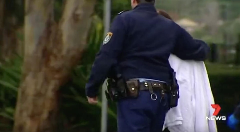 A police officer consoles the grandmother of a five-year-old boy who was fatally stabbed in NSW. Source: 7 News