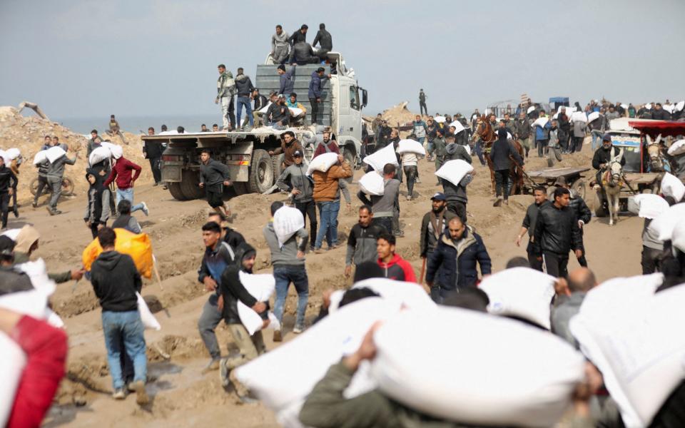 Palestinians carry bags of flour they grabbed from an aid truck near an Israeli checkpoint