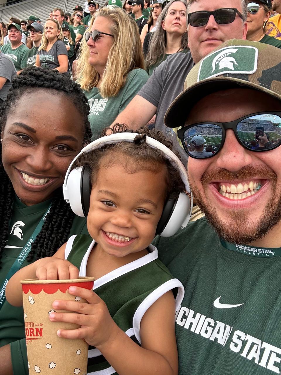 Sharonda McDonald-Kelley, left, and husband Mike Kelley, right, sit with daughter Kyler at Spartan Stadium last fall.