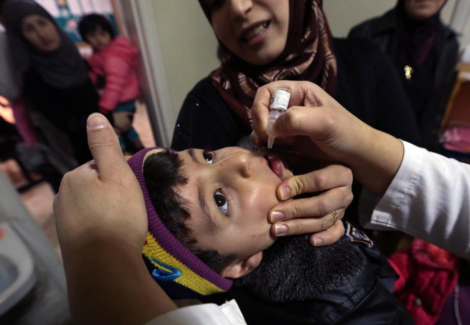 In this Tuesday, March 11, 2014 photo, Syrian refugee Mohammed Sammor, 3, receives vaccination against polio from Dr. Mohammed Anboushi at a medical clinic in the town of Kab Elias in Lebanon's Bekaa Valley. Three years after Syria’s uprising began to overthrow President Bashar Assad, spiraling into a war that has killed over 140,000 people and sending over 2.5 million people fleeing into neighboring countries, aid workers say are now seeing malnutrition emerge, once a barely known scourge in Syrian society. (AP Photo/Bilal Hussein)