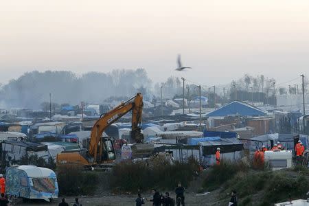 A bulldozer is used to remove debris as workmen tear down makeshift shelters during the dismantlement of the camp called the "Jungle" in Calais, France, October 27, 2016. REUTERS/Philippe Wojazer