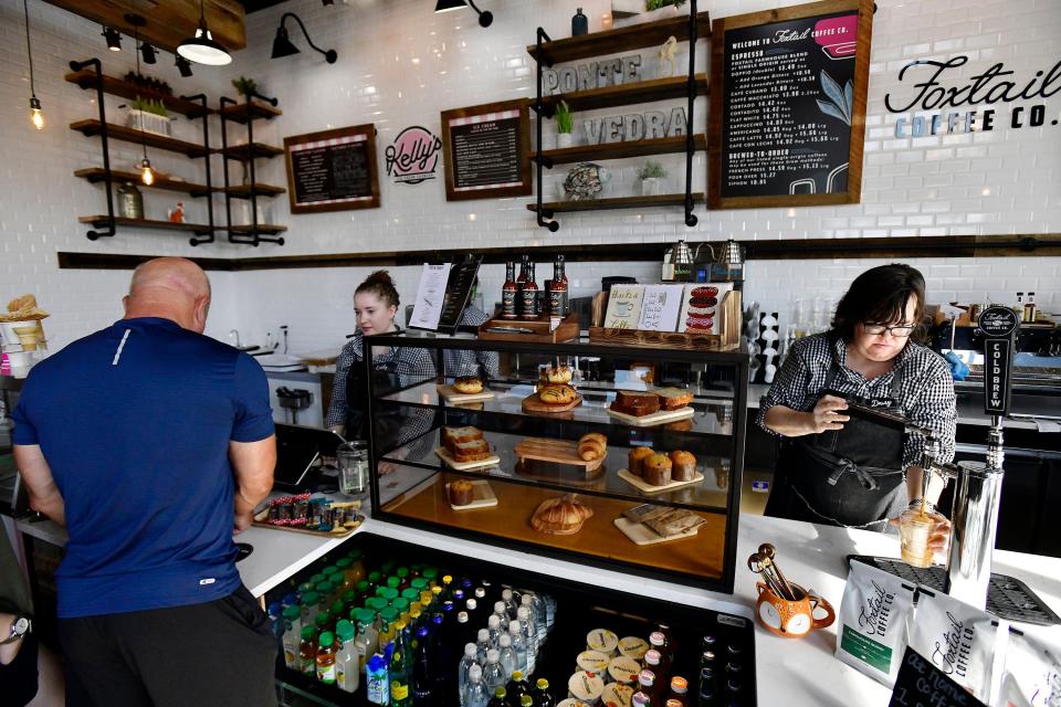 Emily Voykovic rings up a customer while barista Daisy Davenport pours a cold brew coffee from the tap at newly opened Foxtail Coffee Co. in Sawgrass Village shopping center.