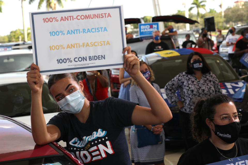 MIRAMAR, FLORIDA - OCTOBER 13: Wearing a face masks to reduce the risk posed by the coronavirus, Sophia Hildalgo (L) and Amore Rodriguez of Miami stay with their car decorated in Cubans for Biden paint as Democratic presidential nominee Joe Biden delivers remarks during a drive-in voter mobilization event at Miramar Regional Park October 13, 2020 in Miramar, Florida. With three weeks until Election Day, Biden is campaigning in Florida.  (Photo by Chip Somodevilla/Getty Images)