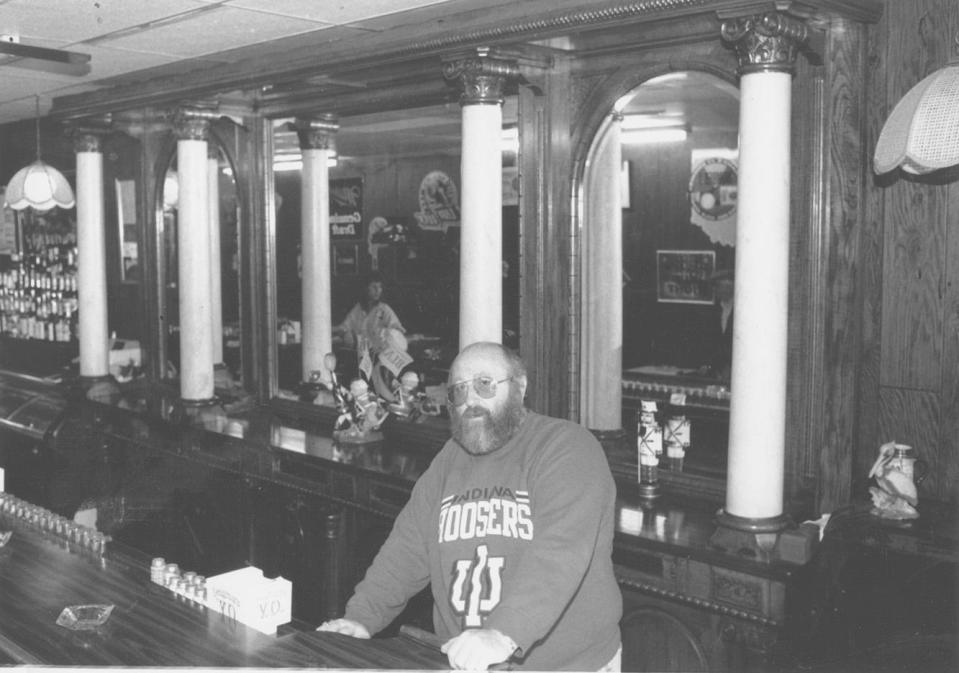 Rusty Abel, who owned Rusty's Tavern from 1990 to 2000, stands at the bar with its intricate carvings and marble columns that remains a feature of the establishment today.