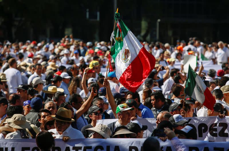 Demonstrators hold up a Mexican flag during a march to protest against violence on the first anniversary of President Andres Manuel Lopez Obrador taking office, in Mexico City