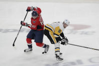 Washington Capitals' Carl Hagelin (62) and Pittsburgh Penguins' Brian Dumoulin (8) battle for the puck during the first period of an NHL hockey game, Friday, Dec. 10, 2021, in Washington. (AP Photo/Luis M. Alvarez)