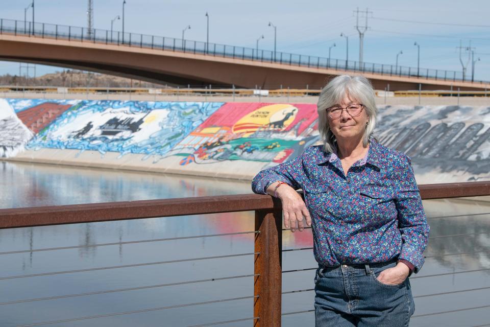 Coordinator for the Pueblo Levee Mural Project Cynthia Ramu stands on the Charles W. Lee Bridge with a view of some of the murals in the background. 