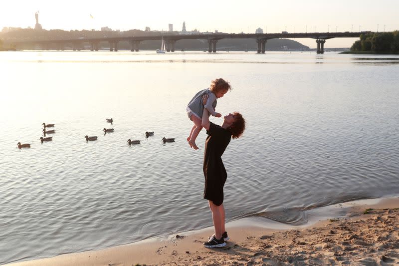 Belarusian electro-folk singer Shukiurava plays with her daughter on a bank of the Dnipro river in Kyiv