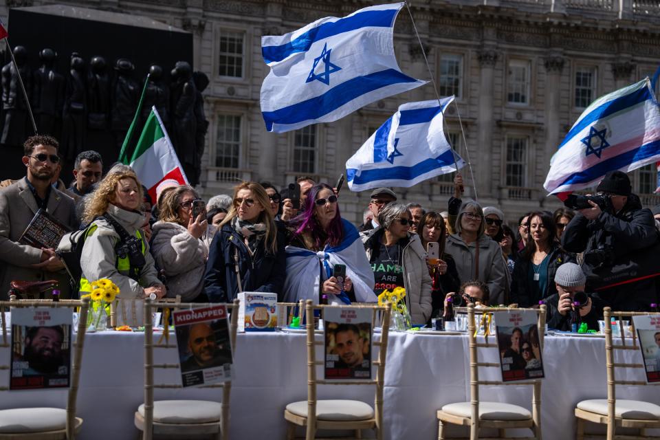 At a demonstration in London on April 17, 2024, people gather around an empty Passover Seder table featuring empty chairs for the hostages taken by Hamas on Oct. 7, 2023.