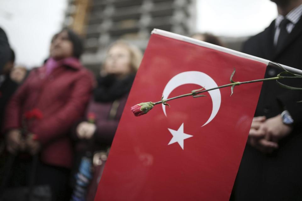 A man waves a national flag as police officers carry the coffin of police officer Fethi Sekin, who was killed in a car bomb attack Thursday, during his funeral in the Aegean city of Izmir, Turkey, Friday, Jan. 6, 2017. Turkey's justice minister Bekir Bozdag says police have detained 18 people in connection with a foiled attack at courthouse in the western city of Izmir that nevertheless killed a policeman and a courthouse employee.(AP Photo/Emre Tazegul)