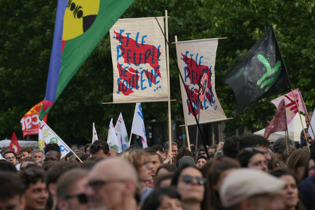 Des manifestants tiennent des drapeaux sur lesquels on peut lire « Le peuple se lève » alors qu’ils participent à un rassemblement contre l’extrême droite place de la République à Paris, le 27 juin 2024. 